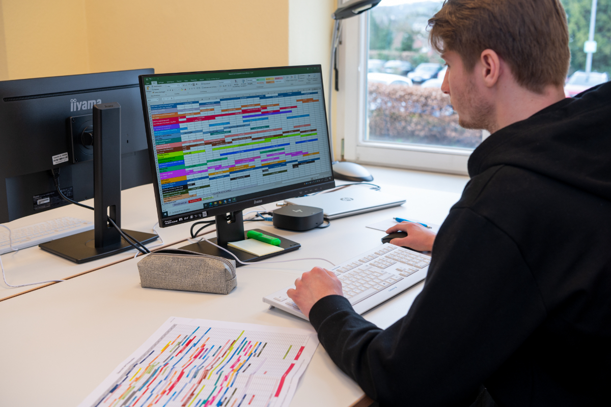 Ein Azubi sitzt am Schreibtisch und arbeitet an einer Excel Liste